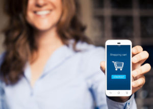 Mujer con un móvil en la mano enseñando carrito de compra de tienda online